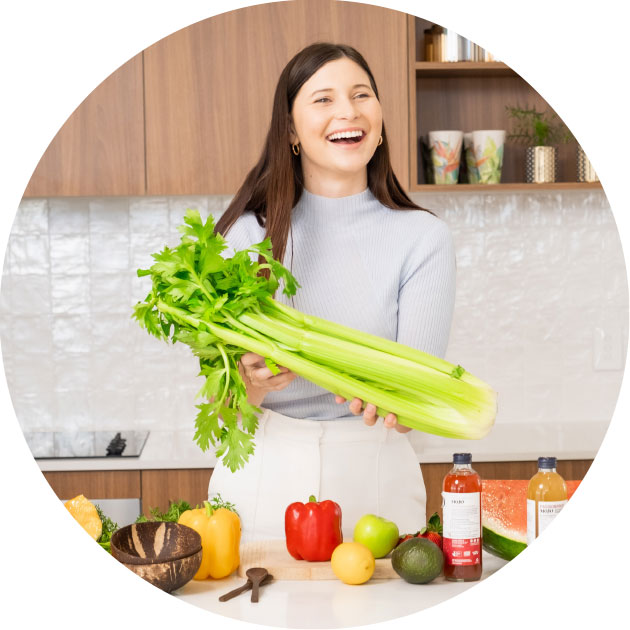 Dietitian standing in a kitchen with mixed fruit and vegetable holding celery