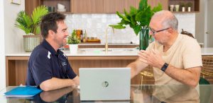 Male occupational therapist talking to male patient at the kitchen table